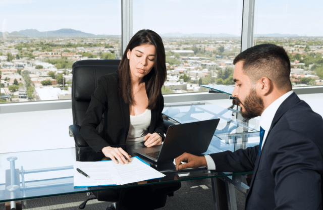 Two colleagues discussing data on a laptop screen.