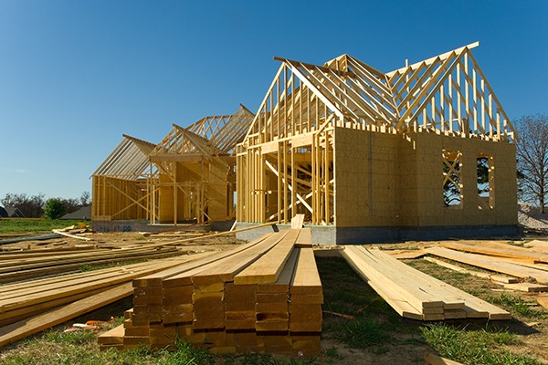 Bright coastal living room with soft natural light, stone flooring, neutral furnishings, and floor-to-ceiling glass opening to an outdoor patio.