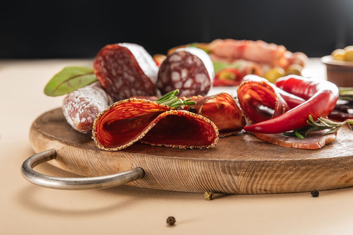 A beautiful seelct of salami and meat slices on a charcuterie board.