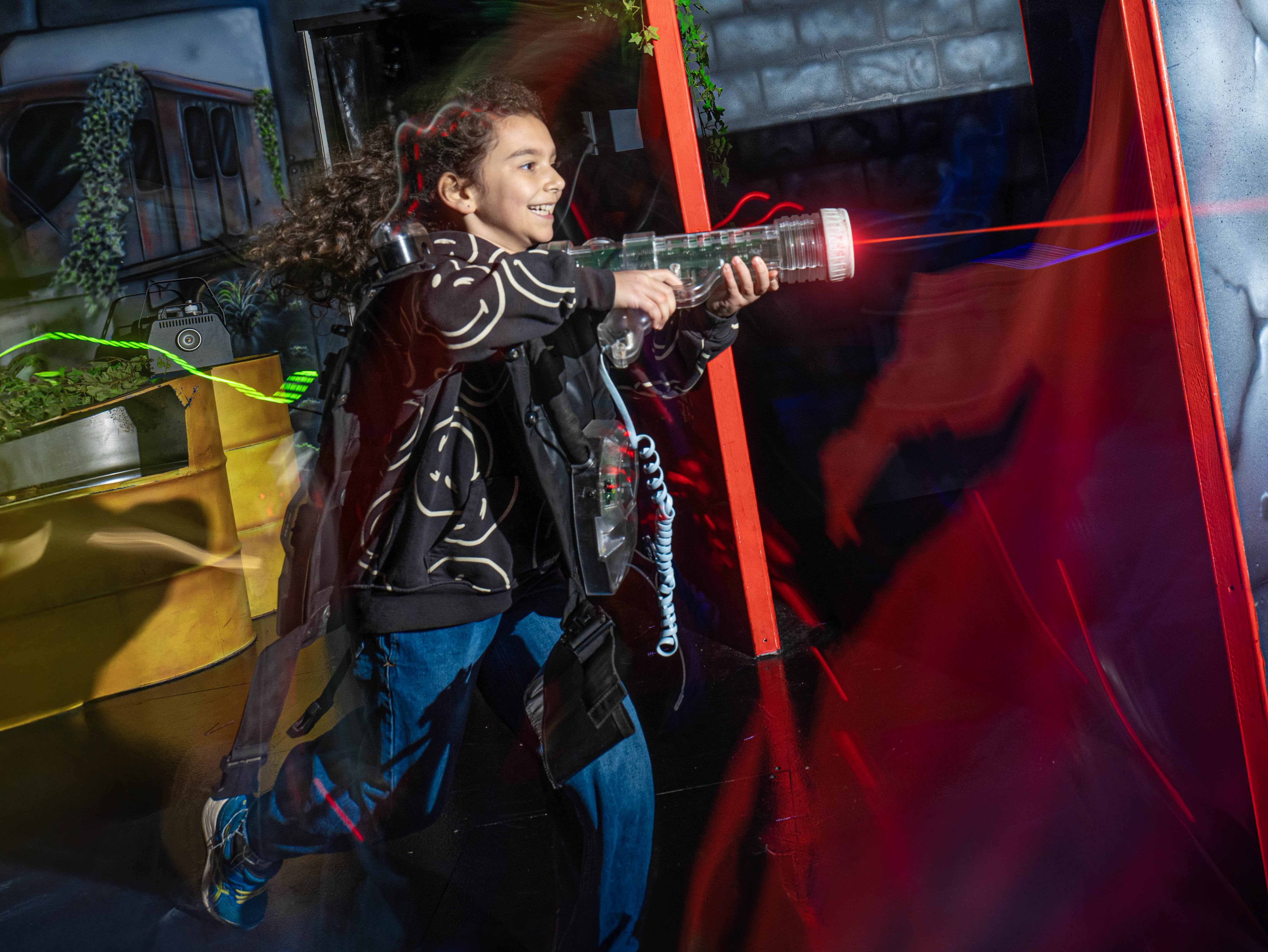 young girl running around with laser gun, having fun at Flip Out Adventure Park