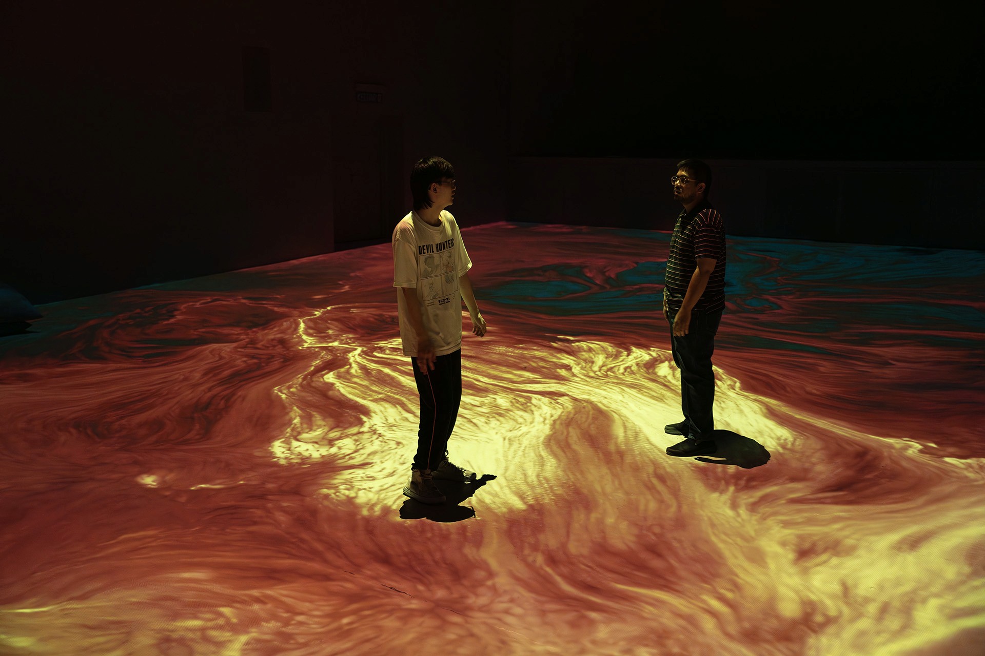 Two people stand on a fiery, swirling-patterned floor.