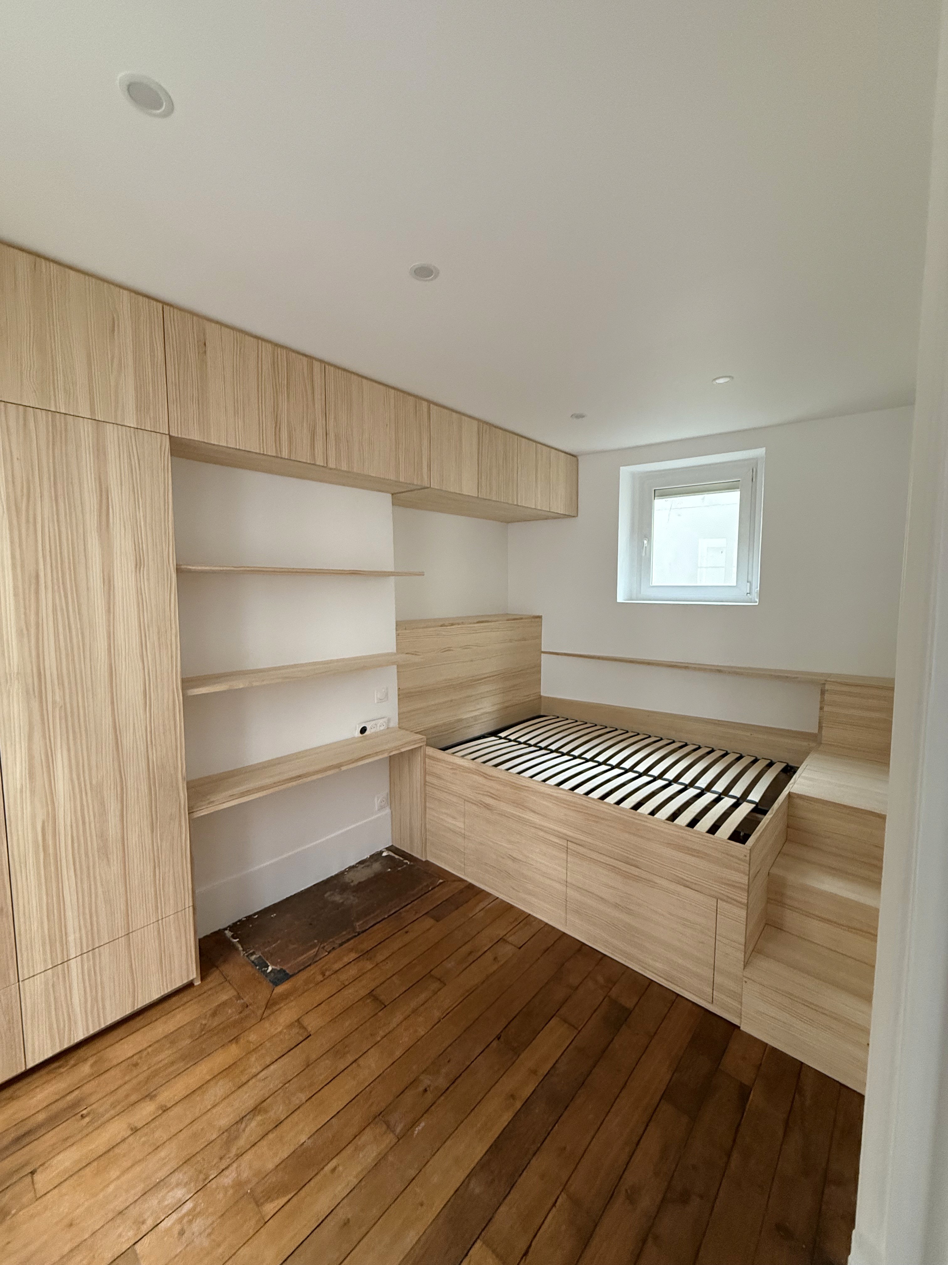 Conception d'un lit podium en bois massif avec tiroirs et escalier de rangement pour une chambre millimétrée.