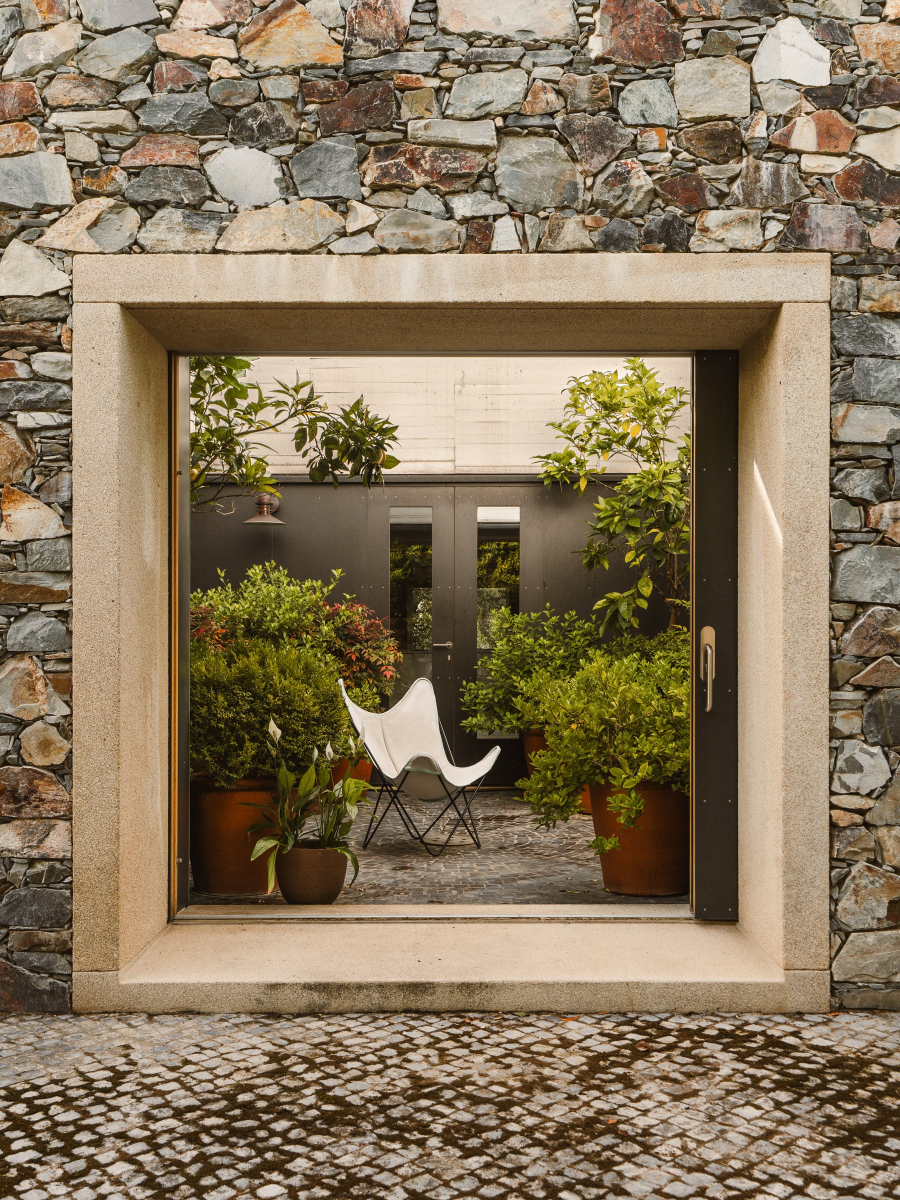 Stone courtyard with a framed view of the garden in a house in Cáceres by Tuñón y Albornoz