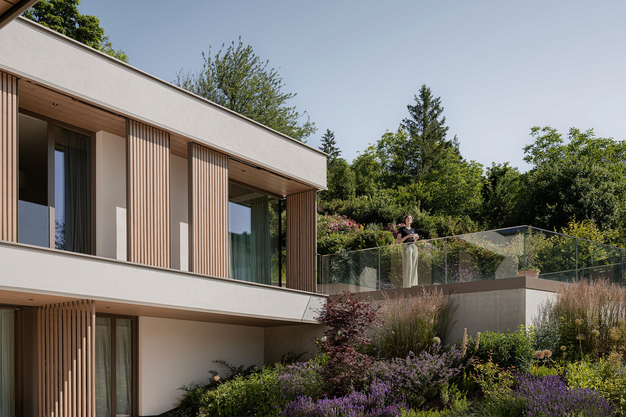 Modernes Wohnhaus mit Terrasse und naturnah gestalteter Gartenbepflanzung.