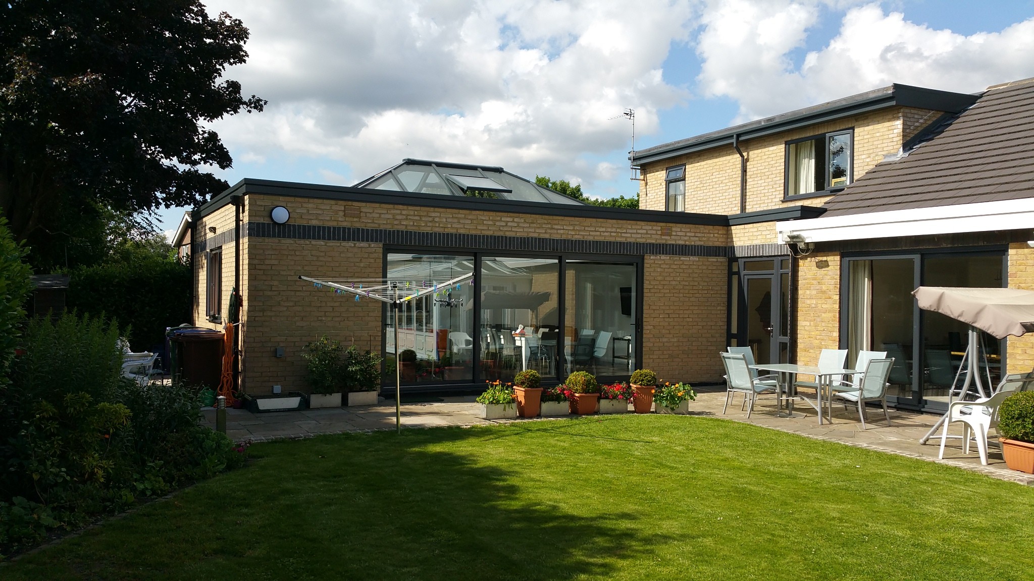Single-storey rear orangery extension with large sliding doors opening to the garden, featuring contemporary brickwork and skylight roof.