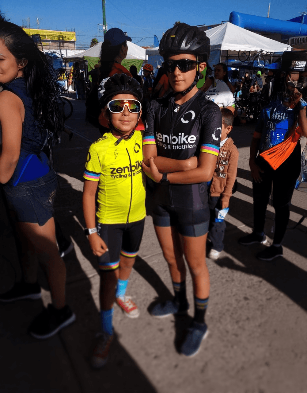 Ciclistas juniors ZenBike con uniforme oficial posan con actitud antes de competir en evento infantil de ciclismo.