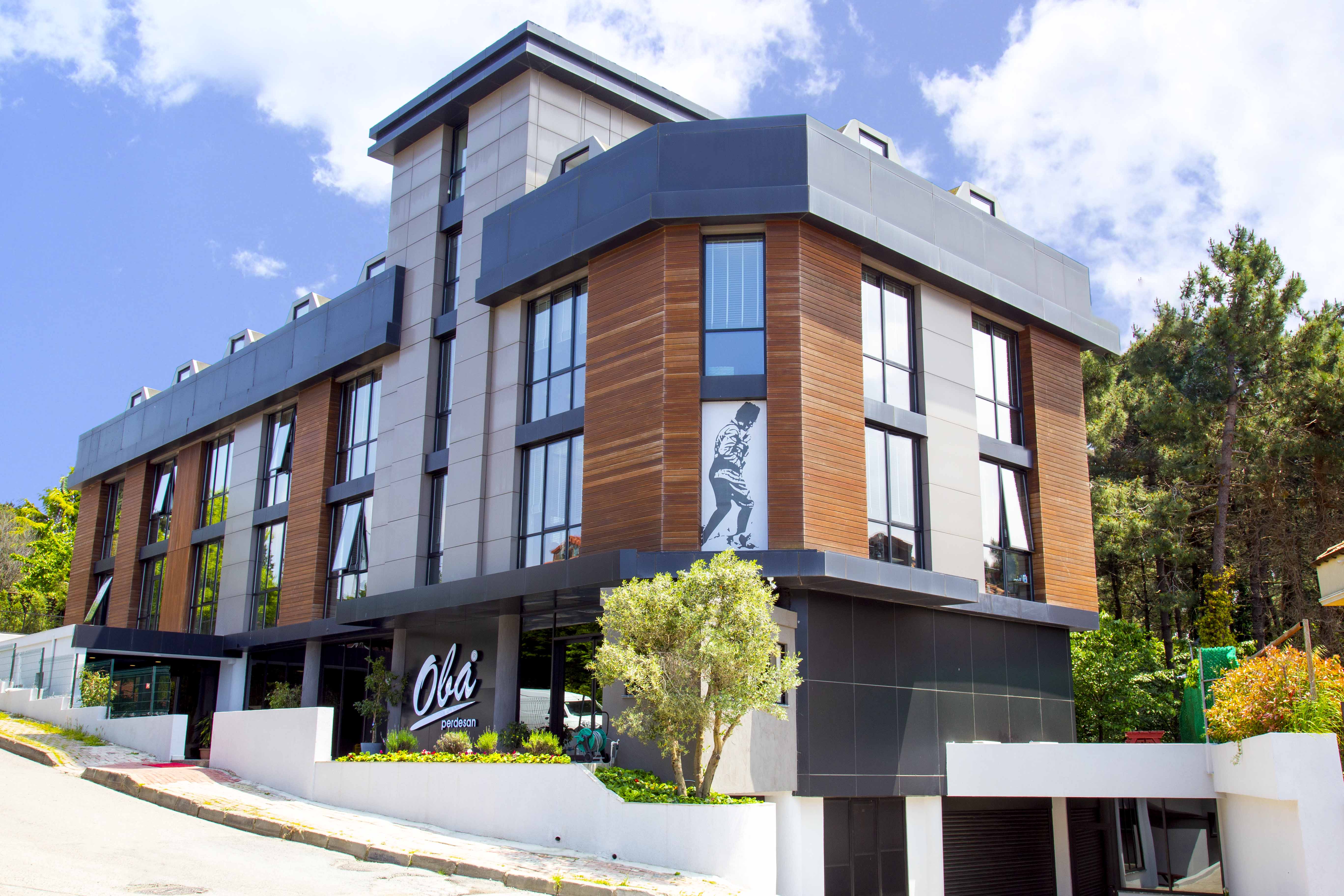 Two people sit across a table in a stylish room with red velvet walls and a large red pendant light. The mood is intimate and modern.