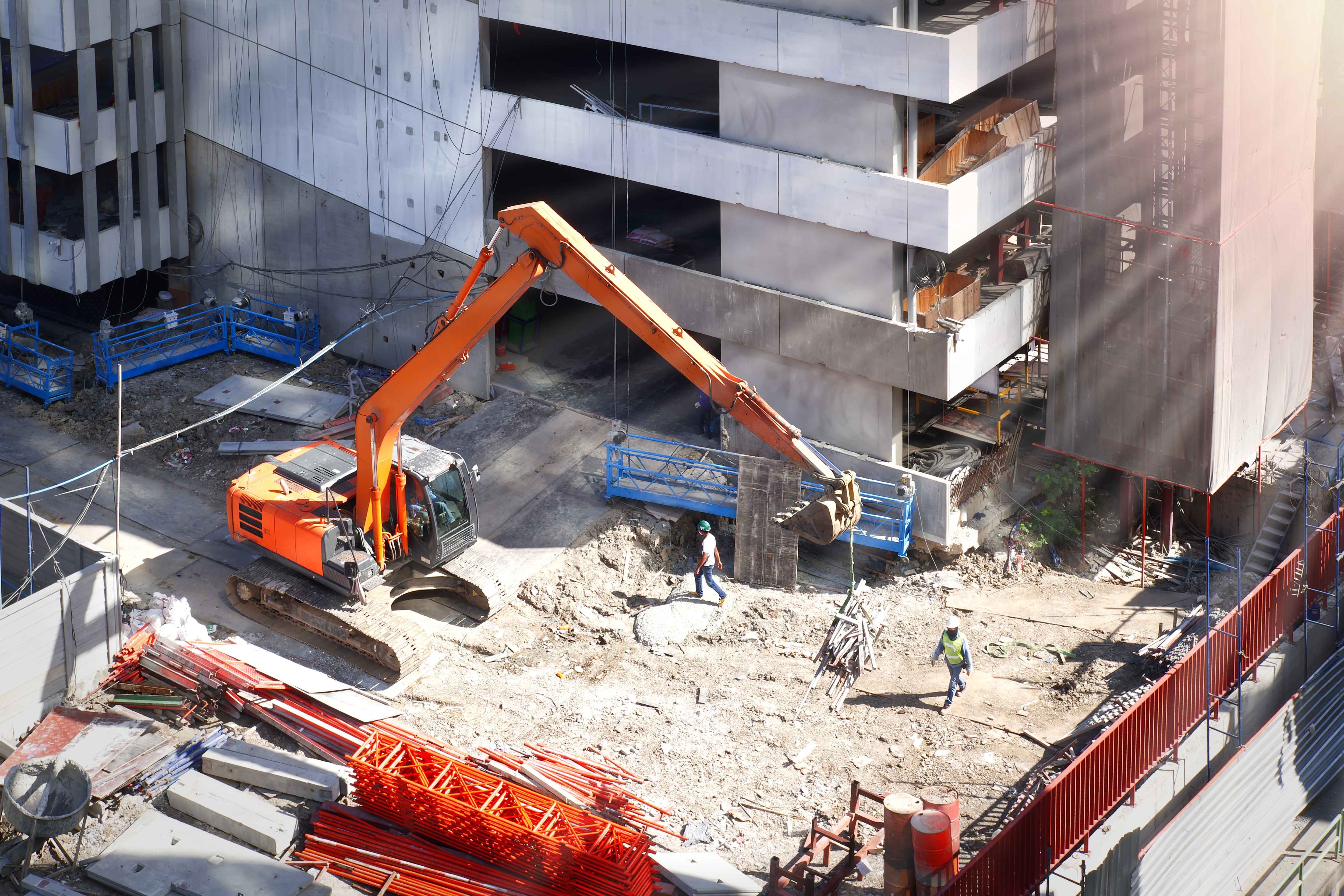 Excavator working alongside construction workers at a multi-storey building site