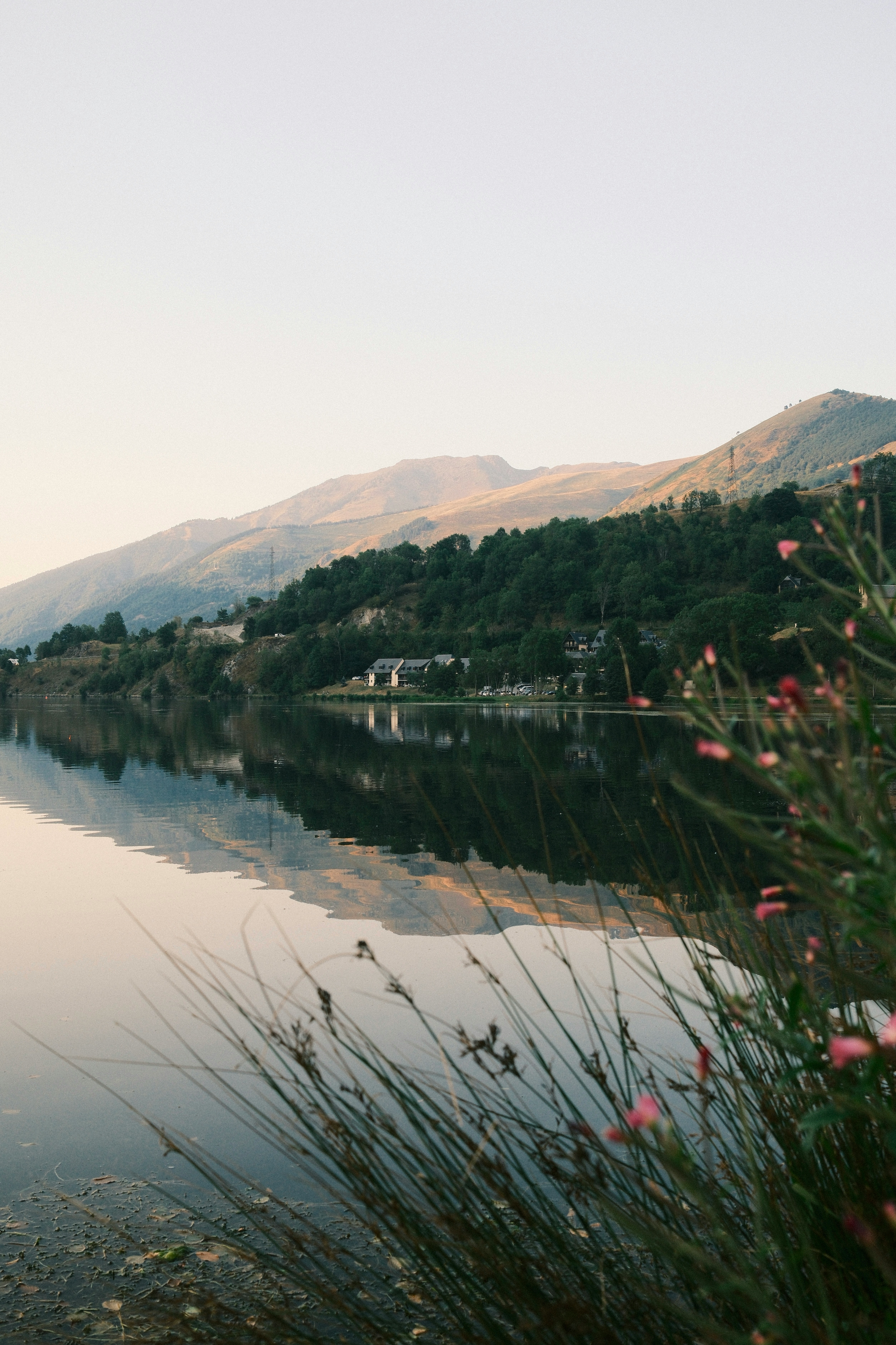 Calm lake reflects mountains and trees at sunset