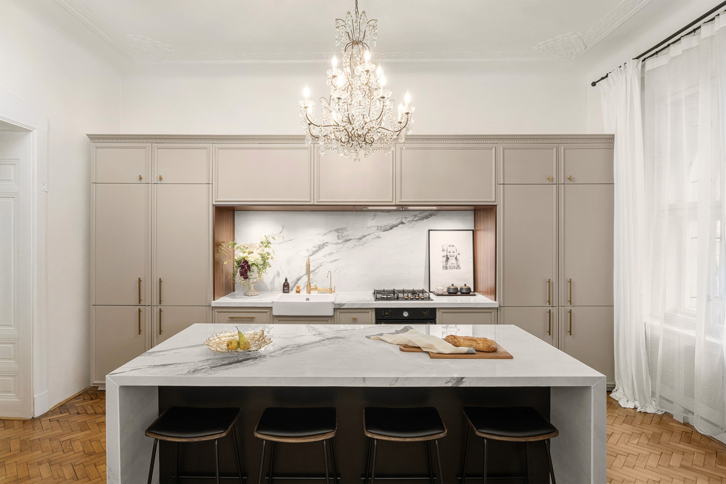 Luxury kitchen interior photographed in Prague apartment featuring custom cabinetry, marble island, brass details and classic chandelier
