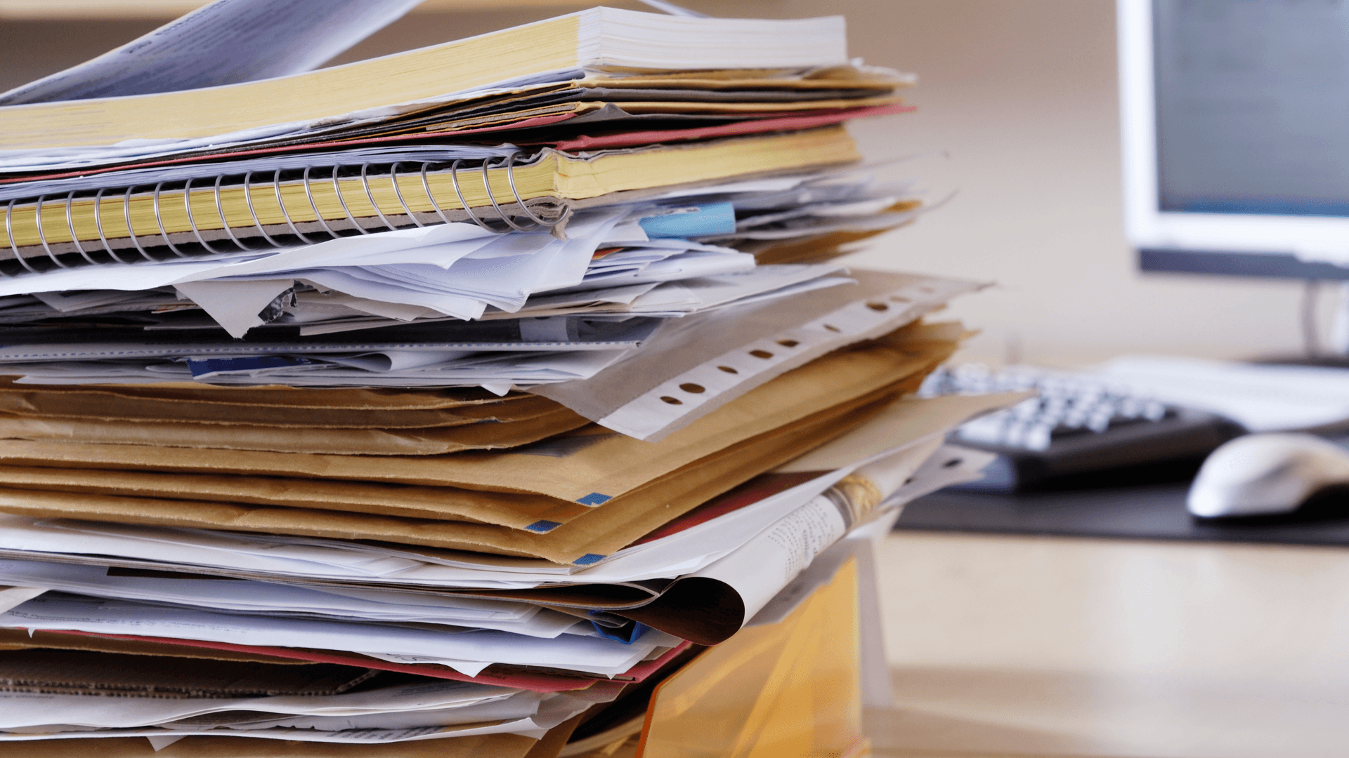 A winding road cuts through rocky terrain, surrounded by patches of green grass and illuminated by sunlight.
