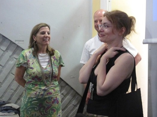 A photo of three people smiling at each other.