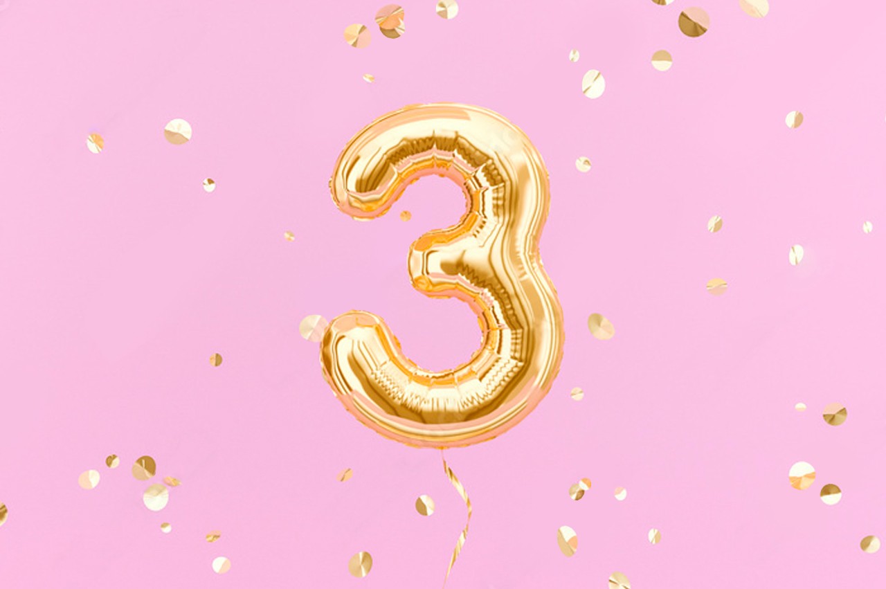 Party balloon in the shape of the number 3 with confetti falling around