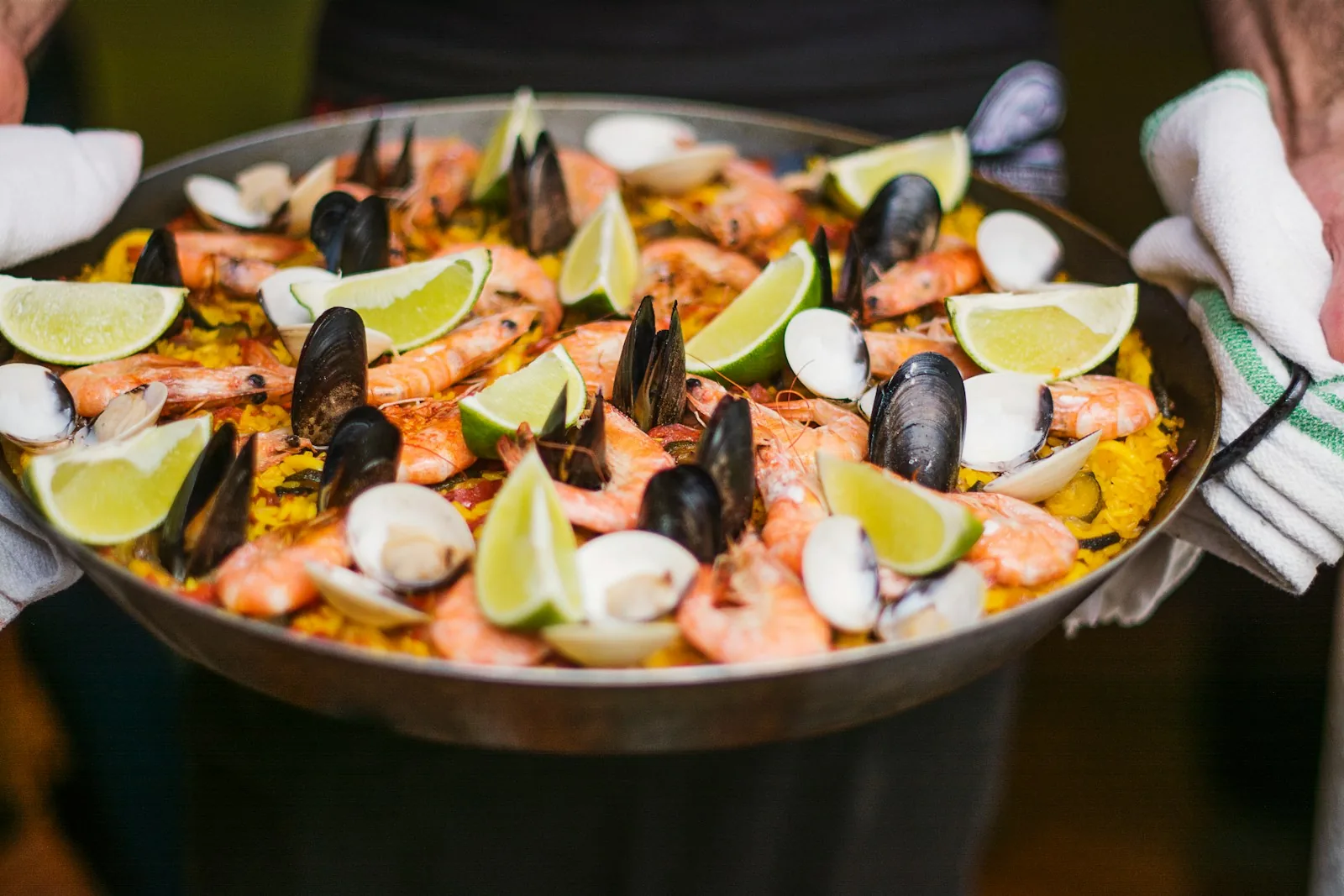 Seafood paella with prawns, mussels and lemon wedges in the pan