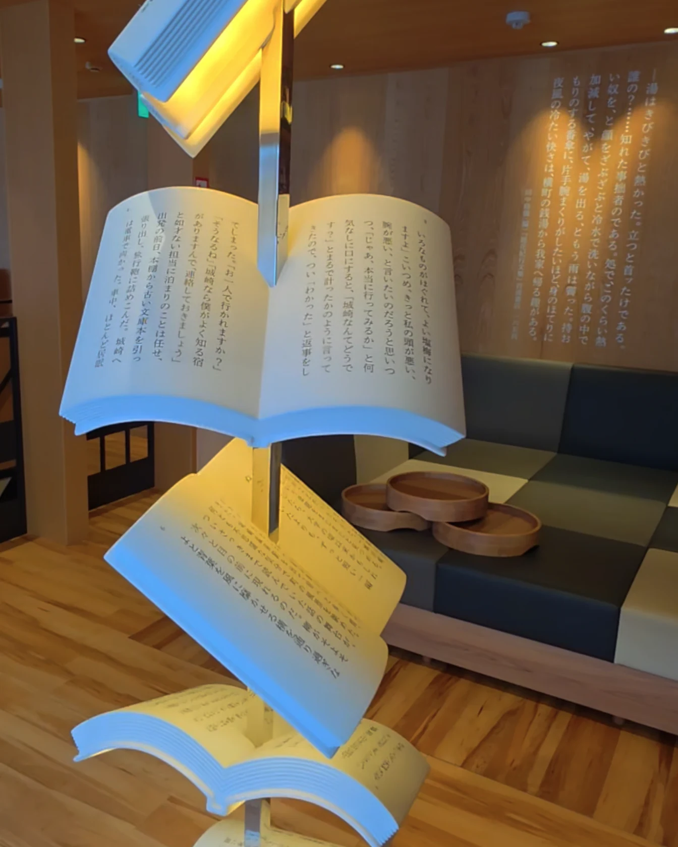 Illuminated open-book sculptures forming a reading display inside the Kinosaki literature museum.