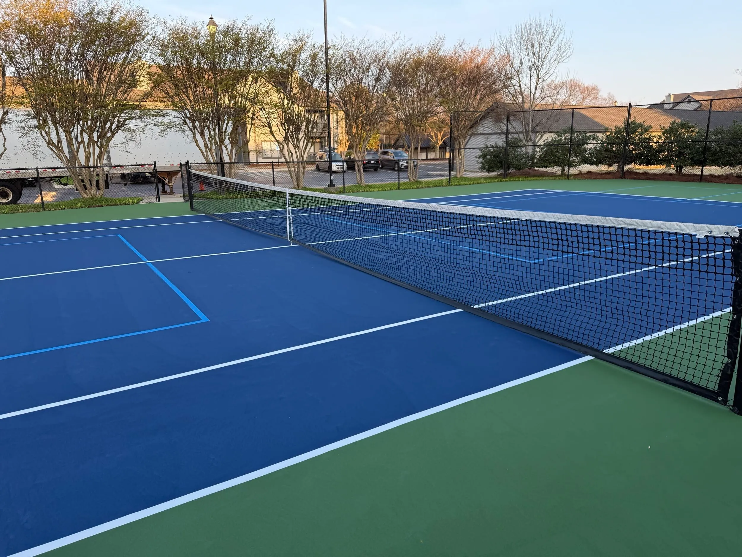 Newly resurfaced tennis court with green out-of-bounds and blue playing surface at Weston Ranch in Madison, AL