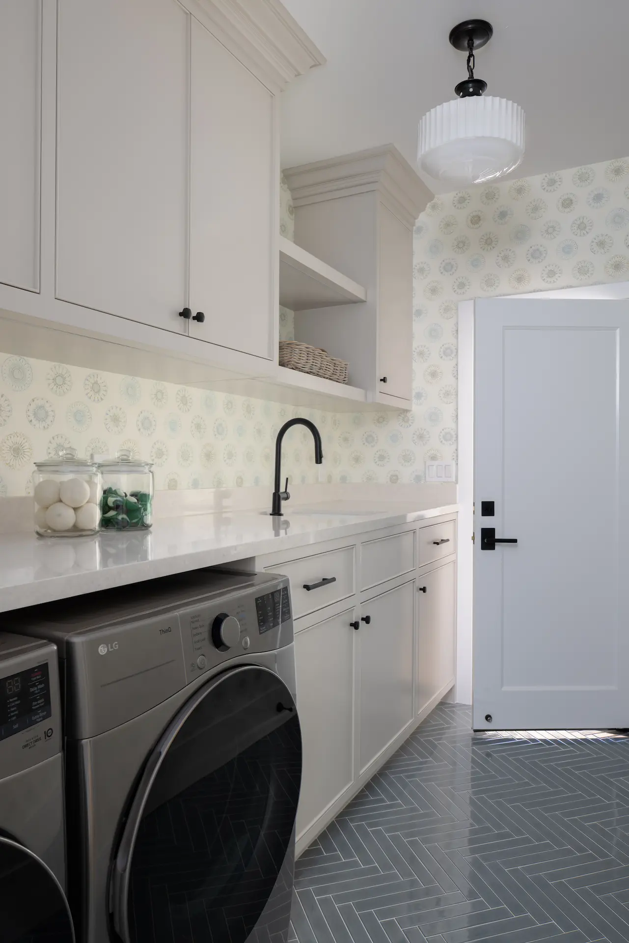 View of the laundry room, featuring custom cabinetry and design in the Irvine Contemporary Coastal Remodel. Photo by Molly Rose Photography.