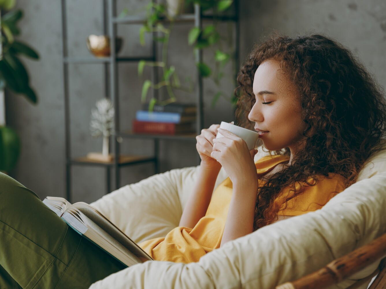 woman taking a rest day with a book and a cup of tea after a week of doing the best type of yoga for weight loss