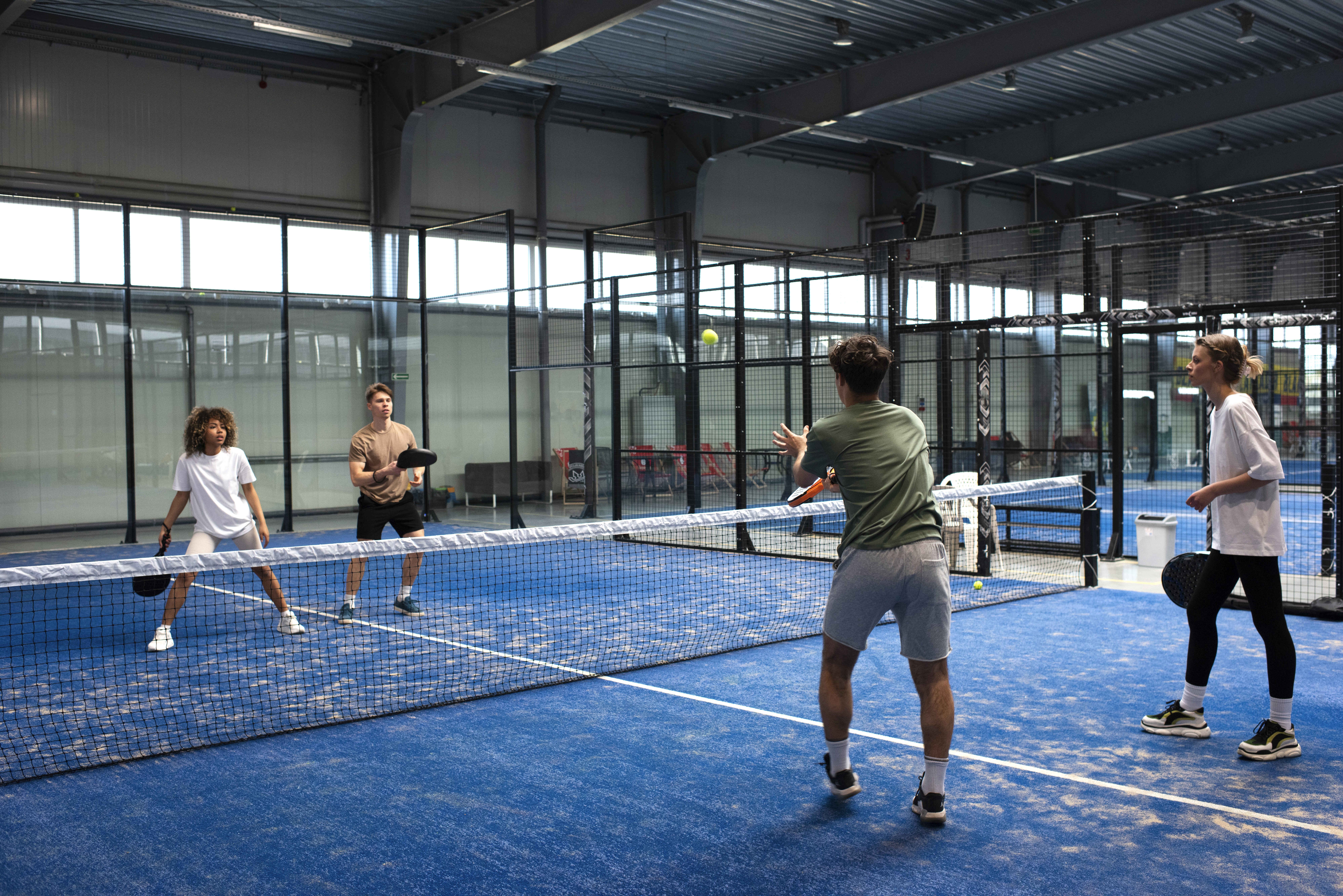 Four padel players playing a match on a padel court