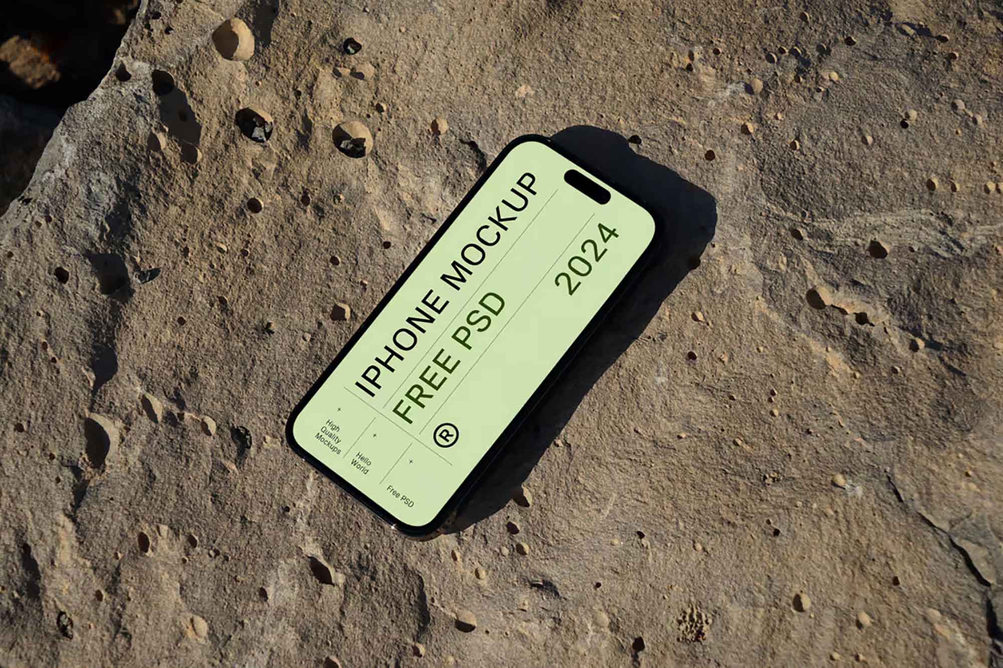 A smartphone with a mockup screen design rests on a textured rock surface. The mockup text reads "iPhone Mockup Free PSD 2024" in bold letters