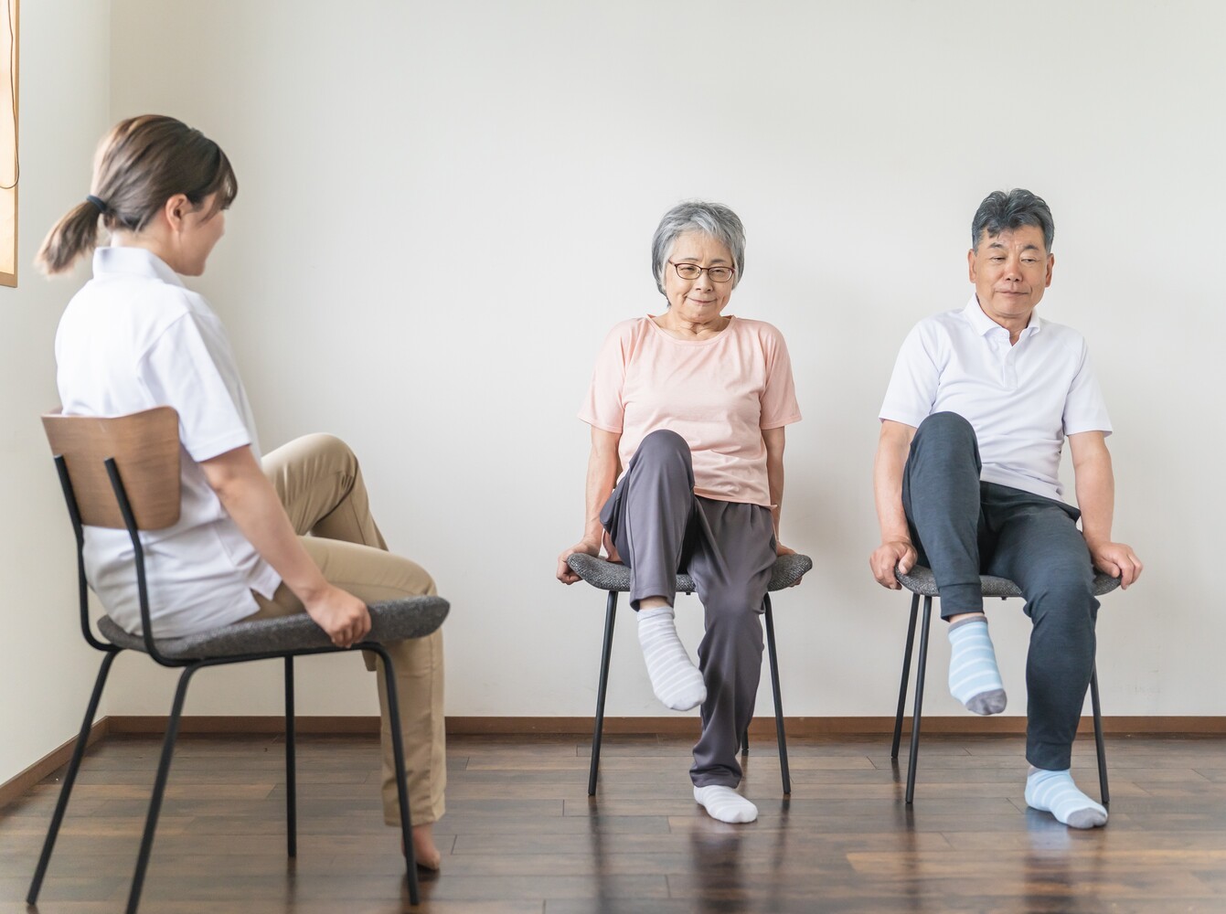 personal trainer taking an elderly couple through seated marching exercises as part of their chair workout routine for weight loss