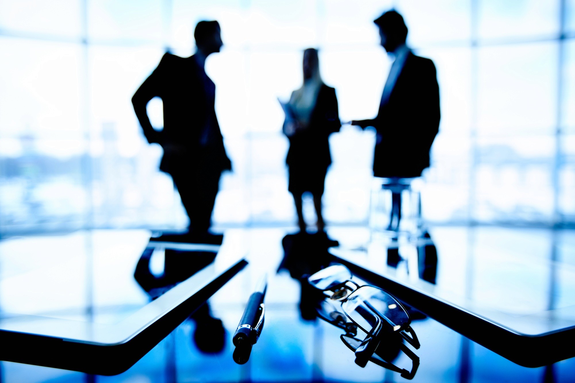 a group of people sitting around a table with laptops