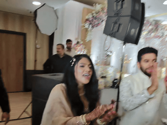 Sarika laughs and claps as a reception dance circle turns toward friends