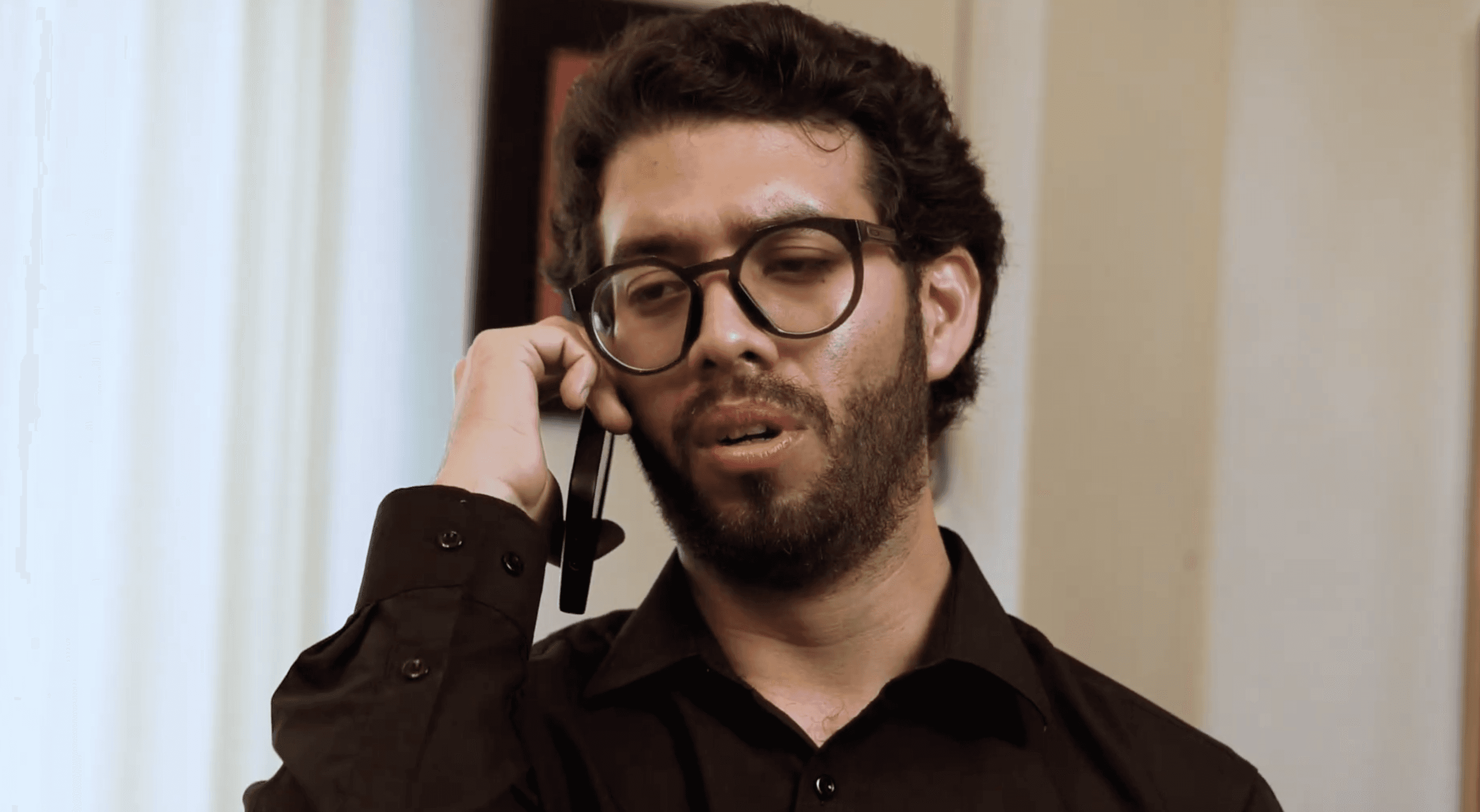 View of the French countryside through a stone villa’s open living room, with sofas and trees framing the scene