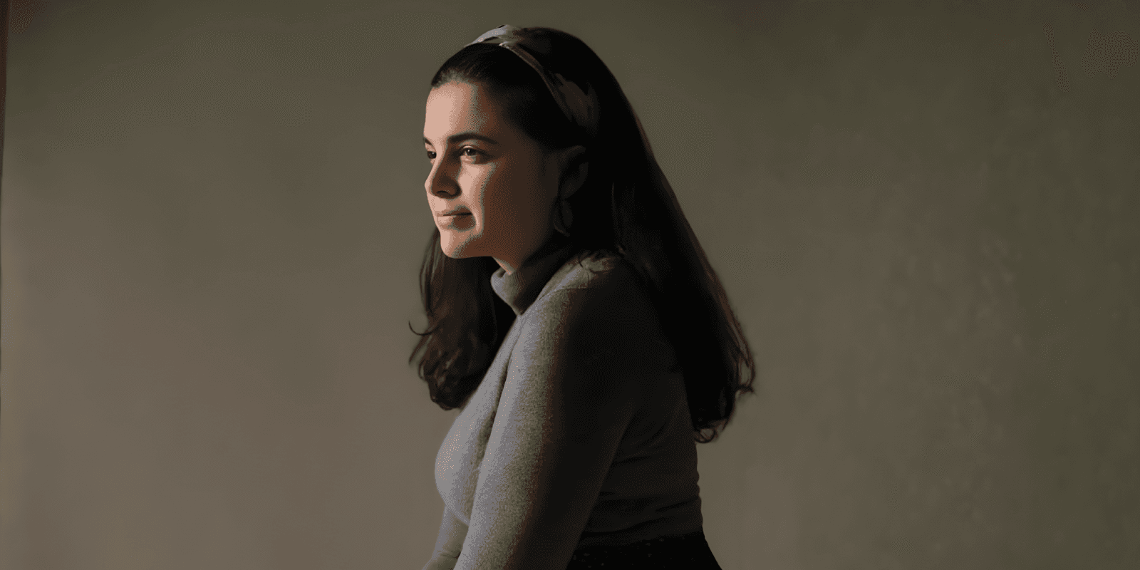 Carolina, a Portuguese-born pop-jazz vocalist, gazes thoughtfully with a serene expression, embodying the emotional depth of her music.