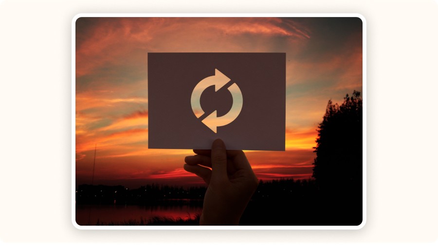 Main tenant carte avec symbole rafraîchissement devant paysage coucher soleil