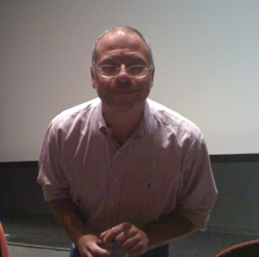 A photo of a person wearing glasses and leaning towards the camera.