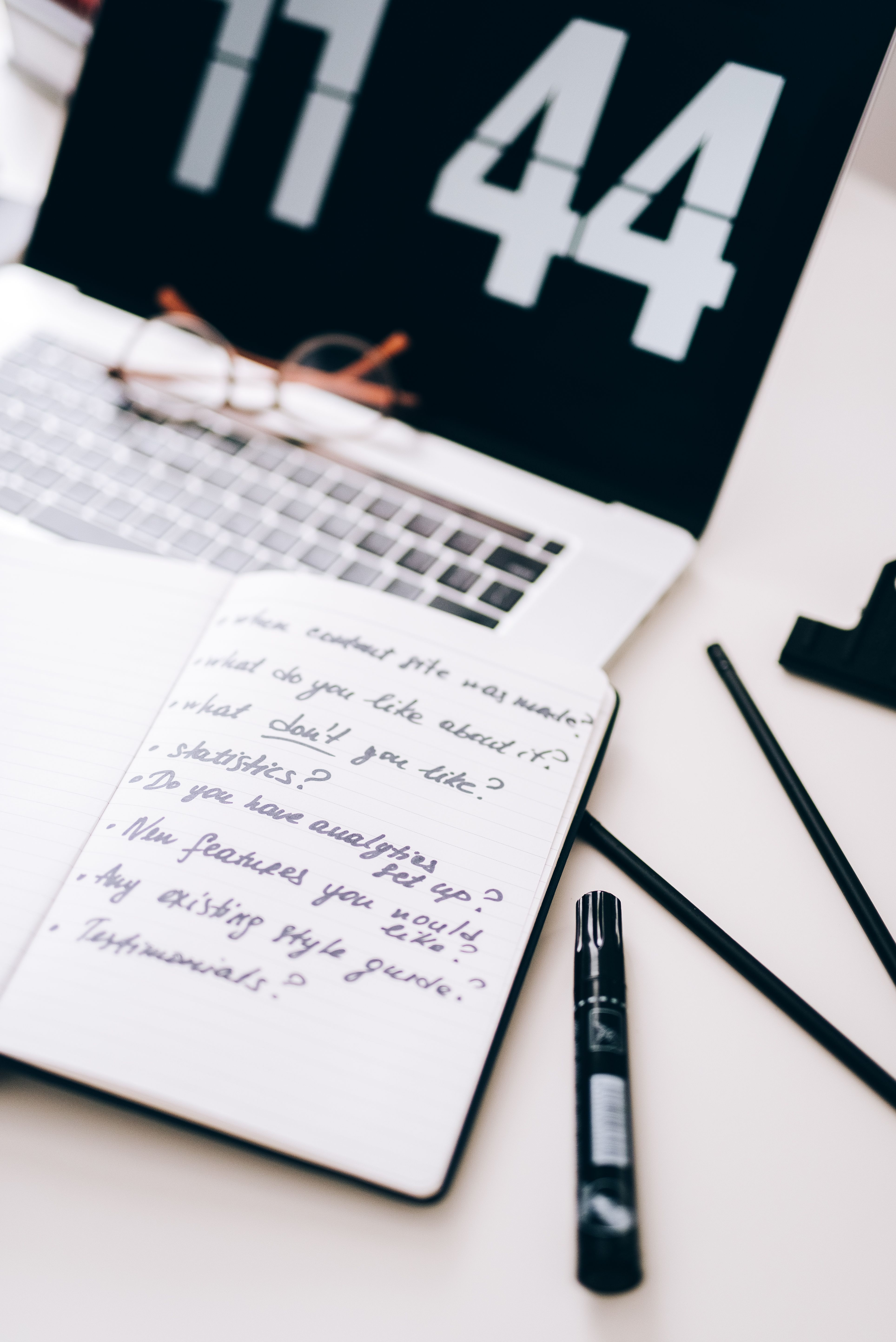 Handwritten list of discovery questions next to a laptop representing sales interview preparation