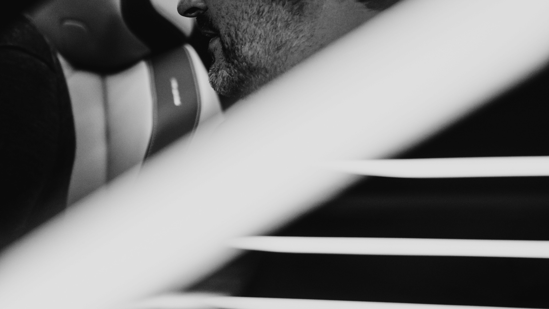 Black-and-white image of a man sitting inside a car in a modern, blue-toned interior