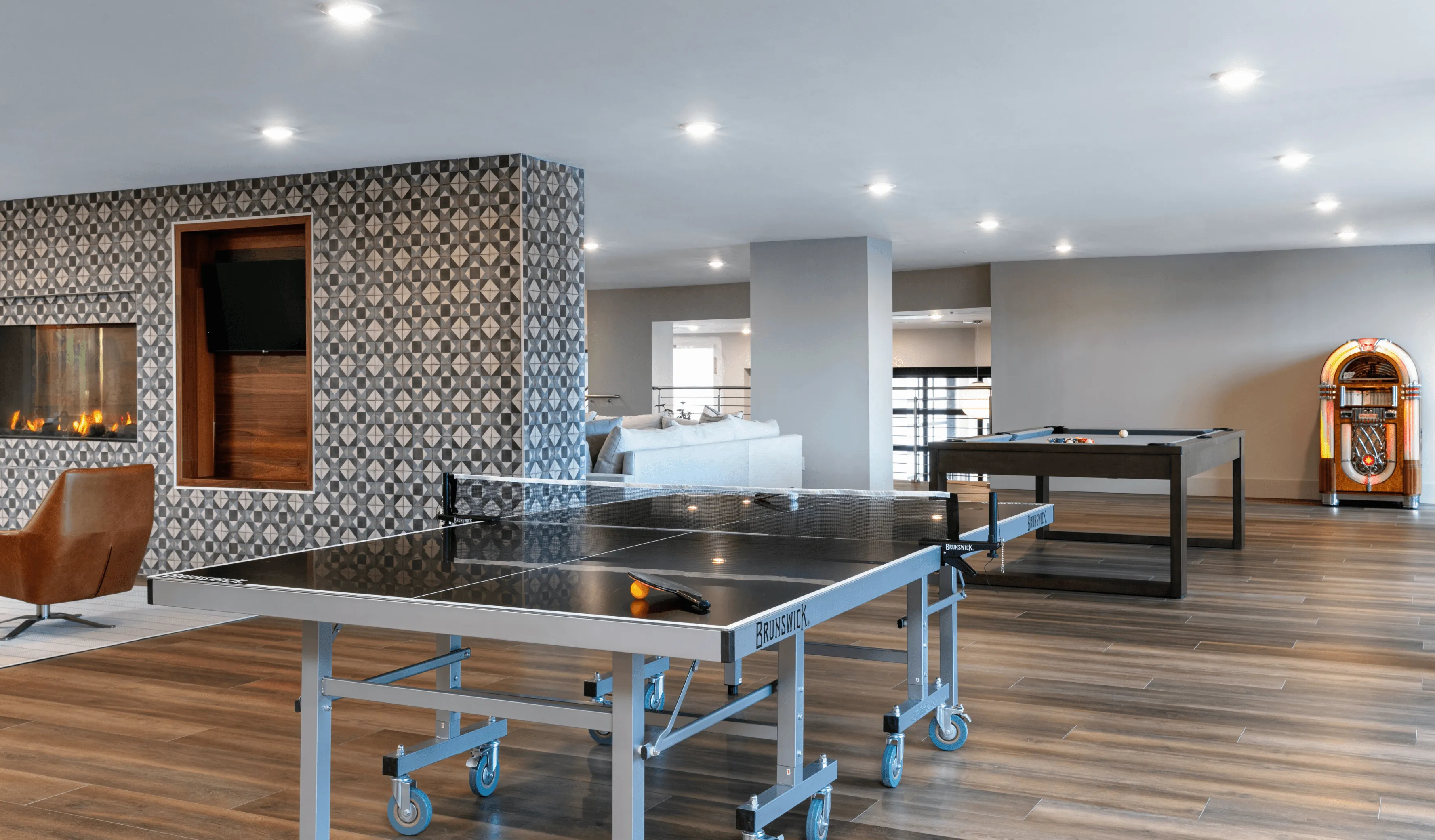 Modern interior of a spacious room featuring wooden elements, large windows, and contemporary lighting fixtures.