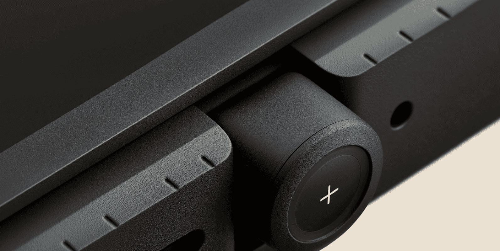 Close-up of a black mechanical part with a round button marked with an “X.”