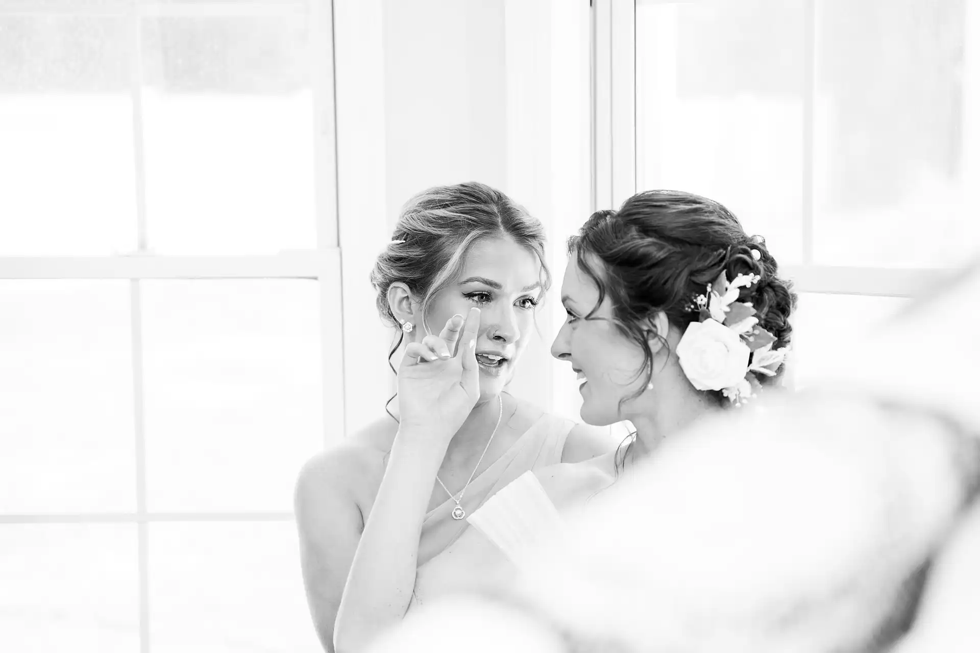  two women looking into each other's eyes while wiping the others tear from her face