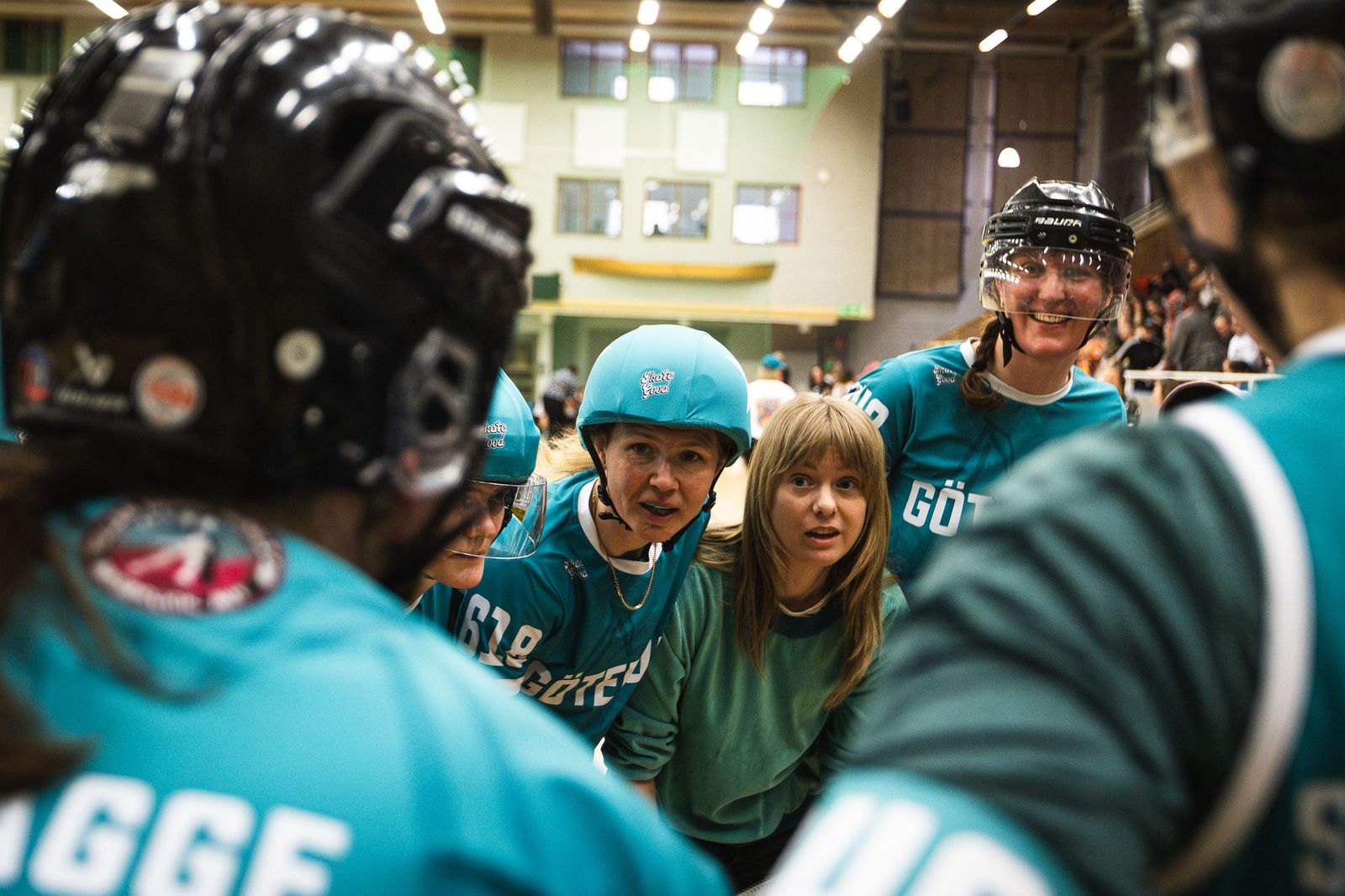 A group of Roller Derby Players in a circle holding each others backs.