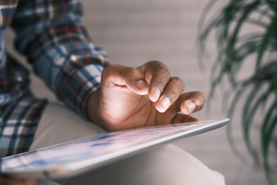 hands using a tablet showing a labor schedule graph, commercial kitchen background with stainless steel surfaces, close-up, managerial focus