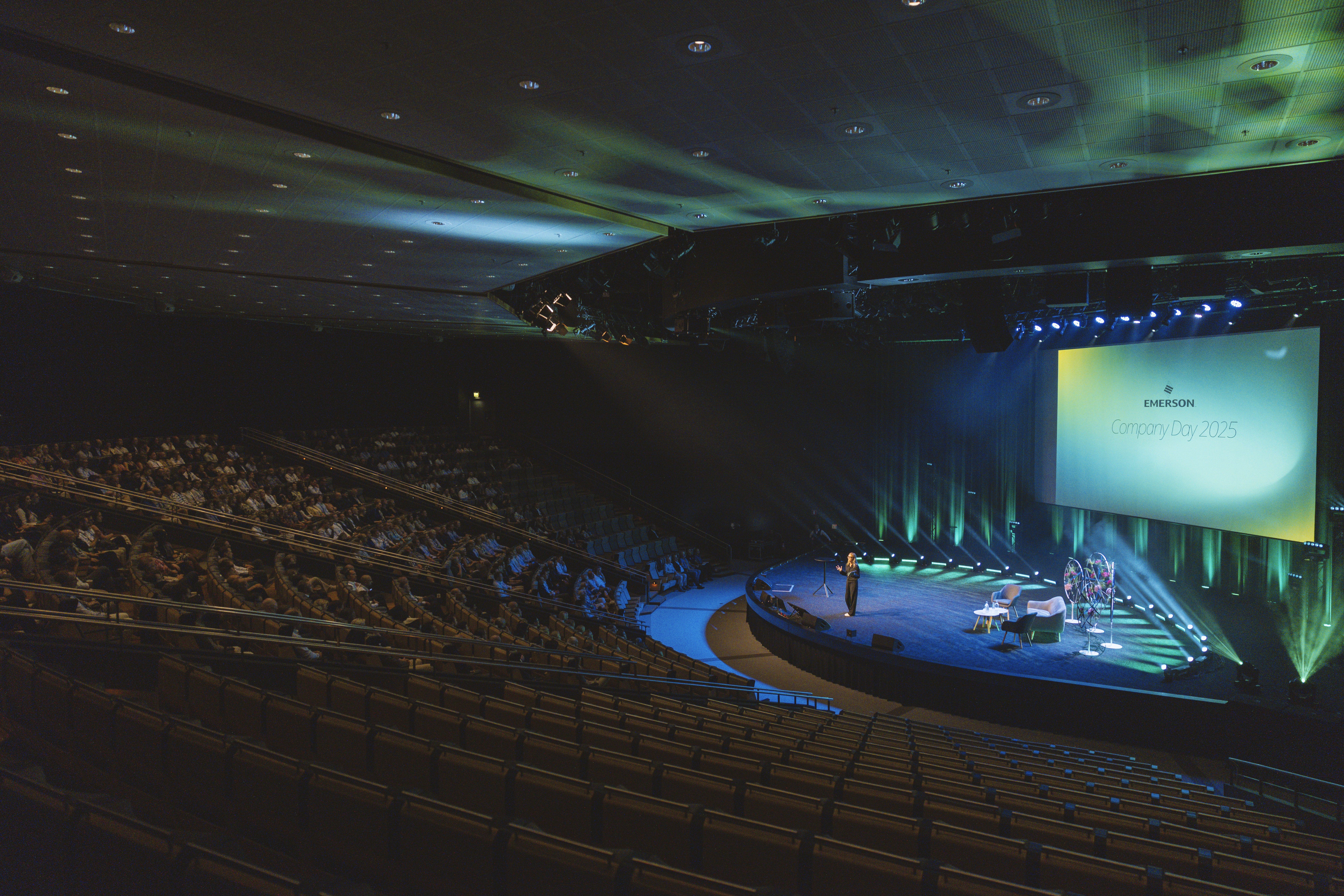 Apresenter standing on a stage talking in front of a large crowd