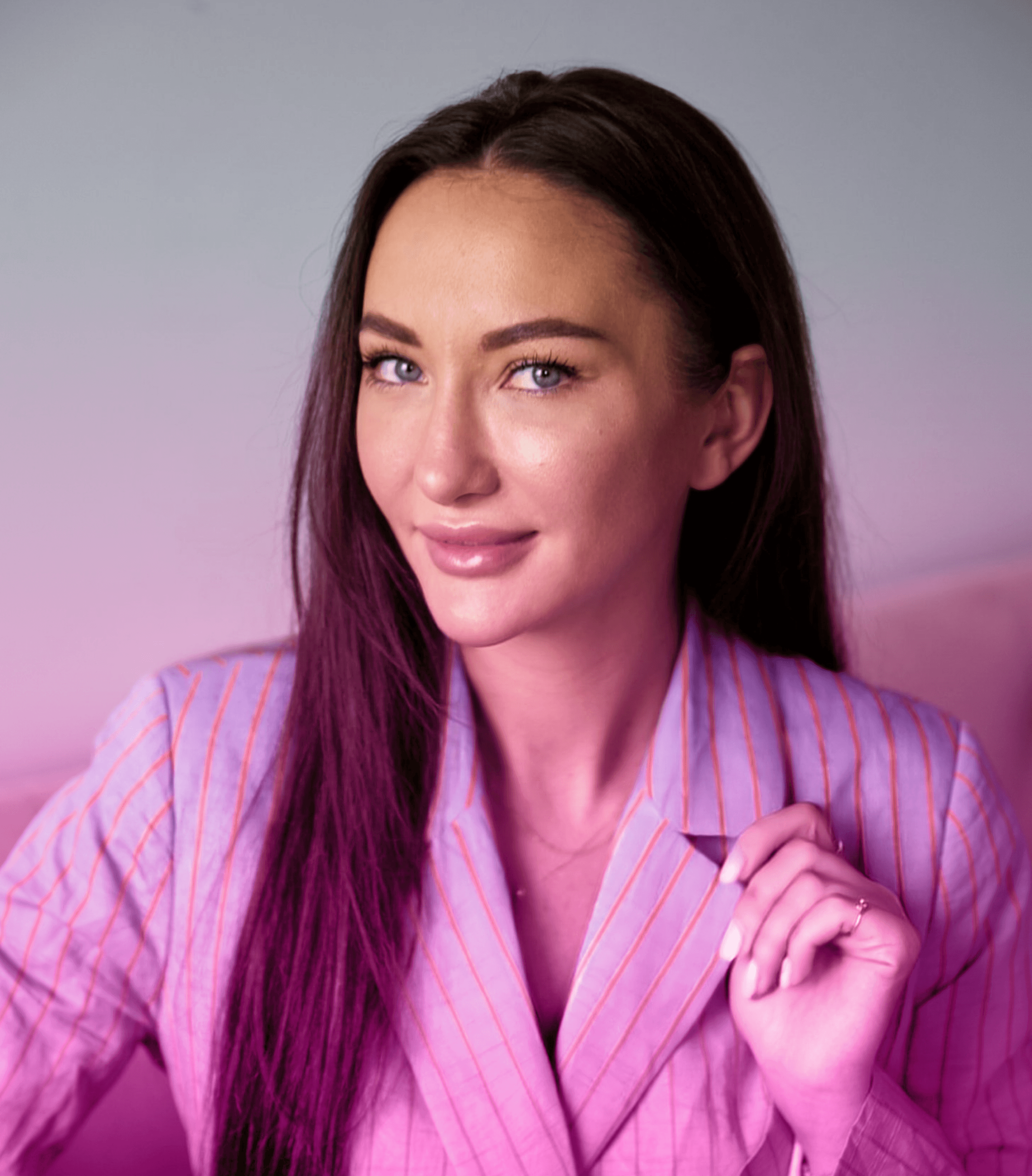Clinic owner in a pink striped shirt, confidently posing in the med spa environment, representing the professional and personalized care provided.