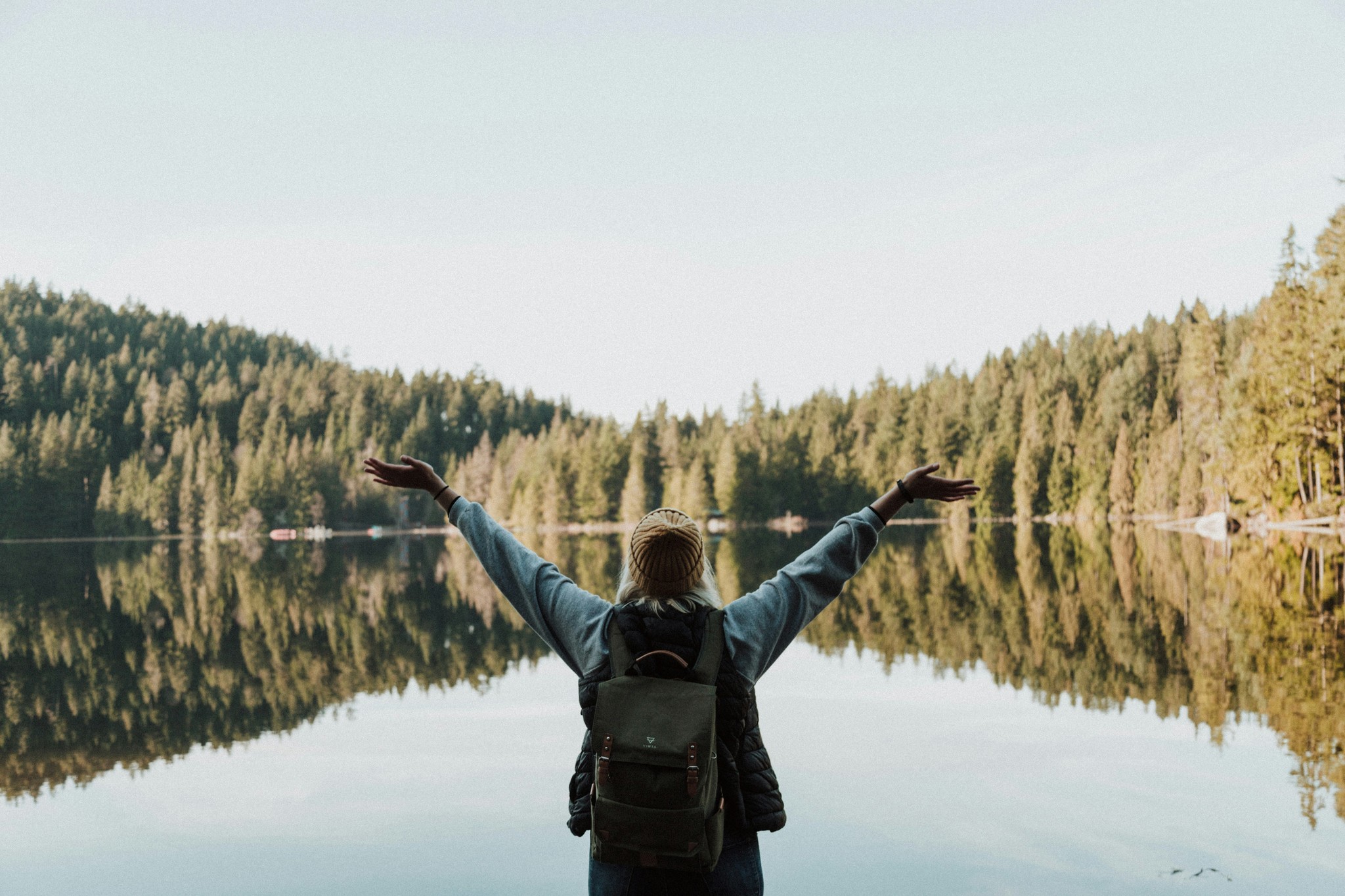 Person with arms open overlooking a lake in the mountains