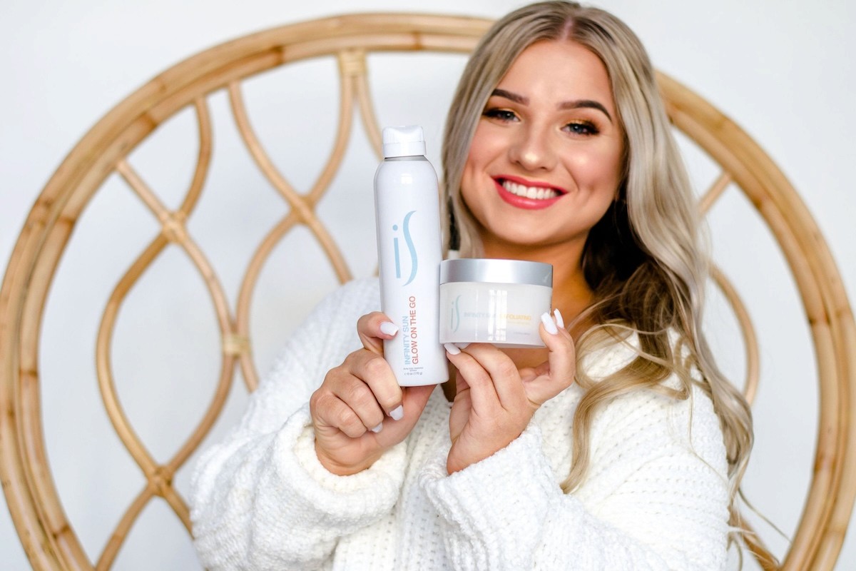 Studio brand photo of smiling woman holding tanning mousse and body lotion products for GottaGettaTan.