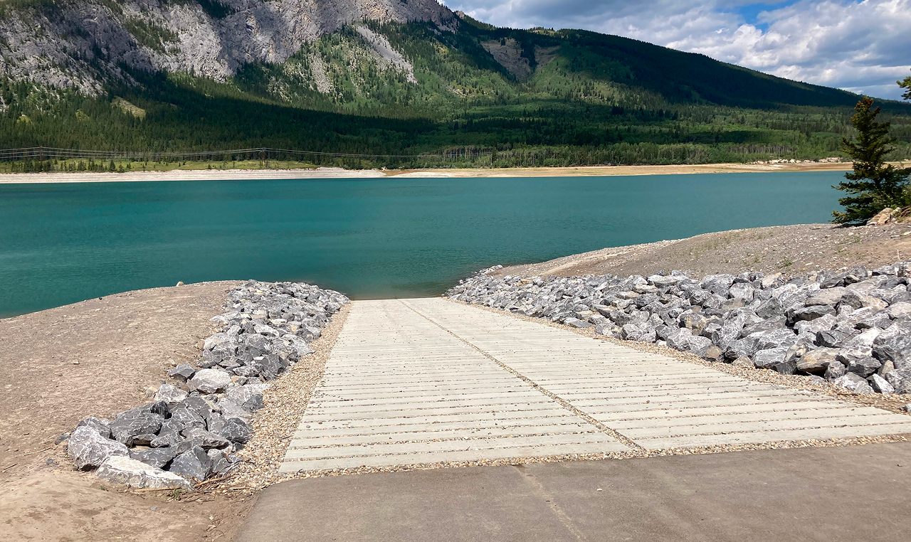 Completed boat launch ramp extending into Barrier Lake with forested Rocky Mountain slopes