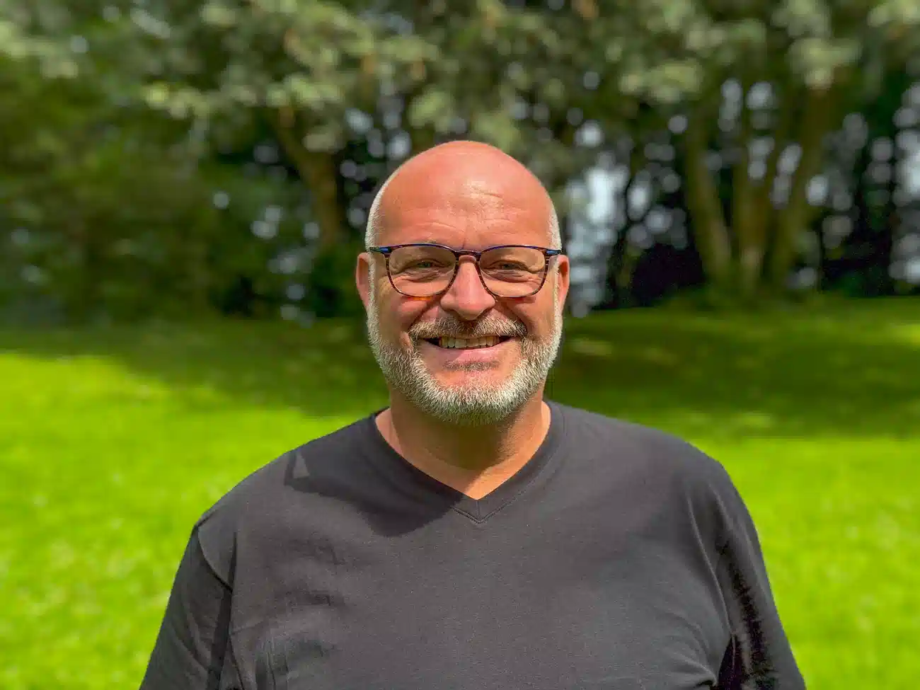 Portrait of Christian Reindl, Co-Founder and CFO of CoachingArea, standing outdoors in a green setting. Christian is the president of the local football club TSV Ludwigsfeld and a former EVP at a FinTech DAX corporate. He managed a budget volume in the billion EUR range and led a team of over 70 employees. He is focusing on finance, sales, and partner relations for CoachingArea.