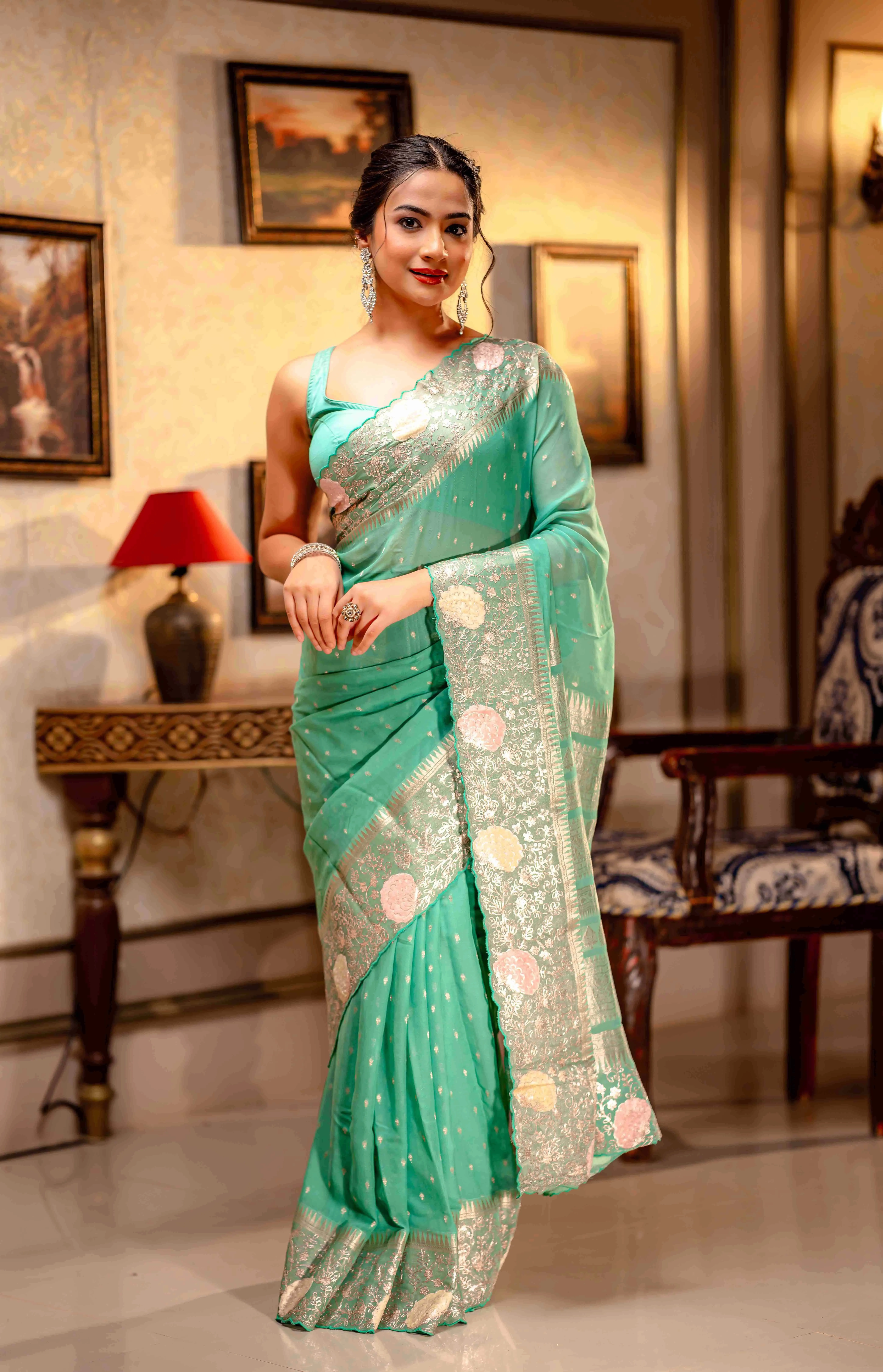 A woman wearing a medow green saree with golden borders from That Saree Shop, in an elegant room, highlighting the saree’s luxurious weave and classic festive charm.