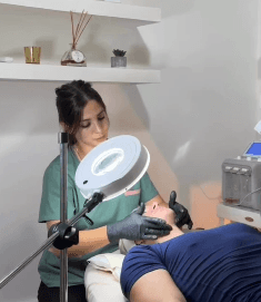 A woman with a white headband relaxing, her face illuminated by warm sunlight filtering through blinds, casting striped shadows. She has a serene and peaceful expression.