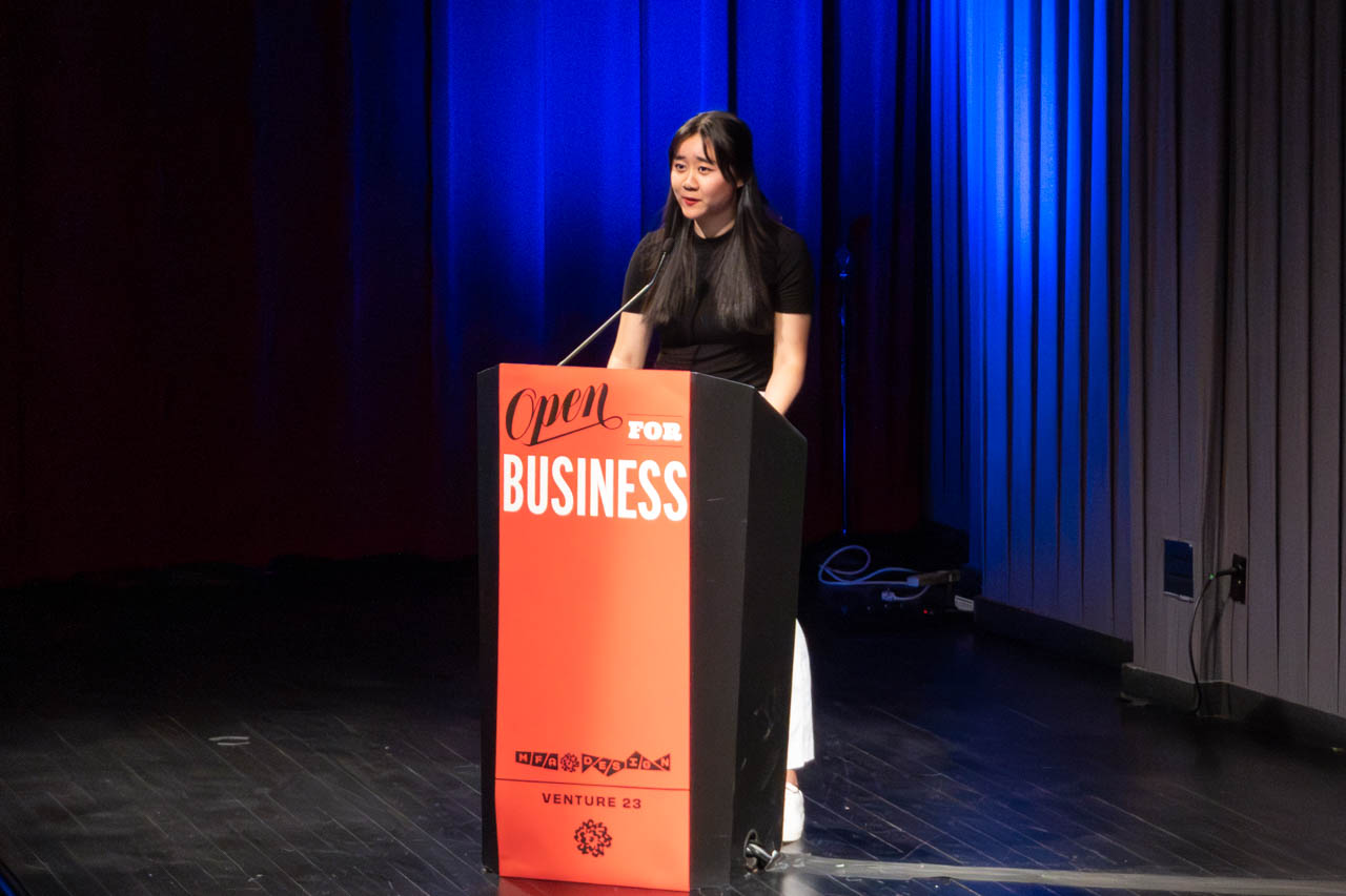 woman standing at a podium delivering a presentation