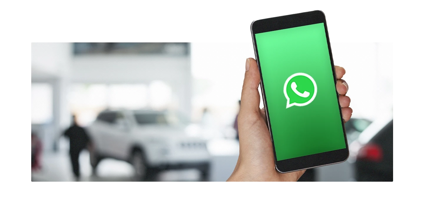 Funcionário de uma concessionária segurando um celular com o símbolo do WhatsApp