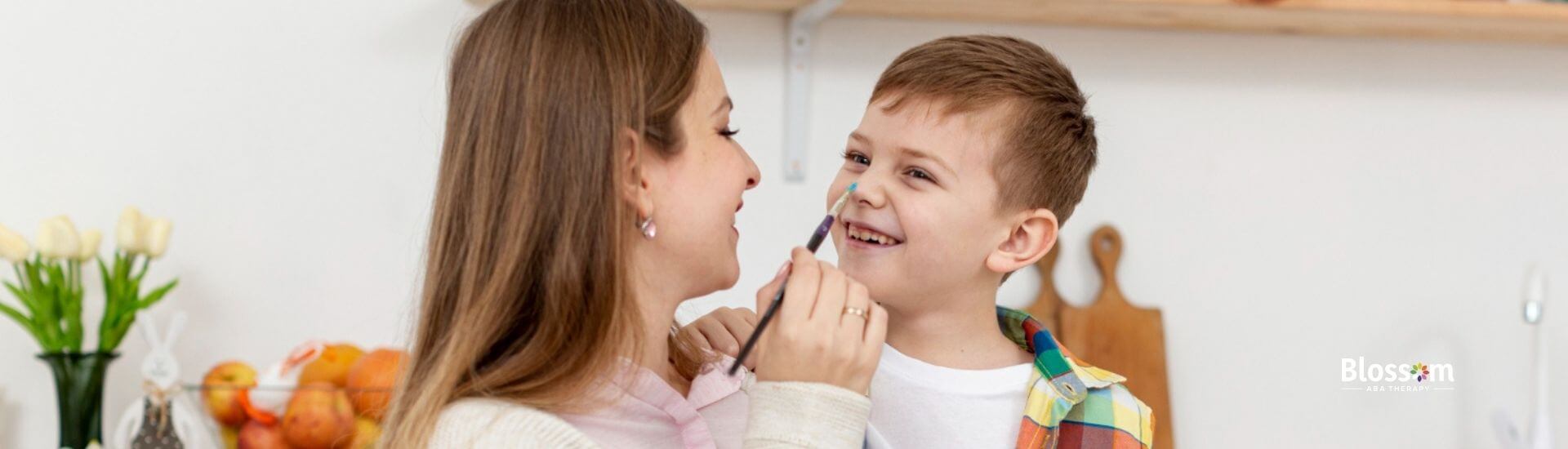 ABA therapist and boy with autism painting eggs together in ABA therapy.