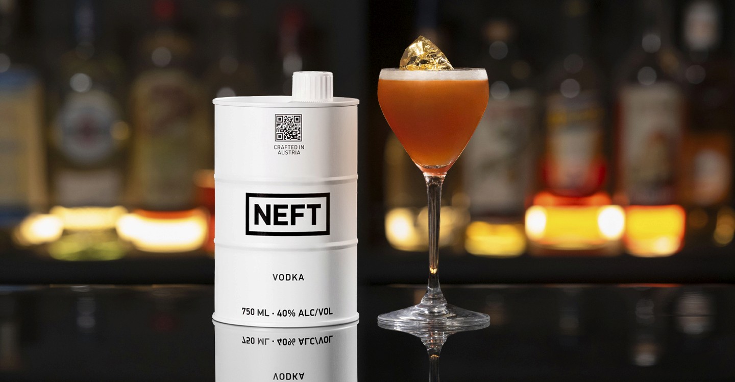 A NEFT Barrel and a glass of 84 Gold on a bar counter.